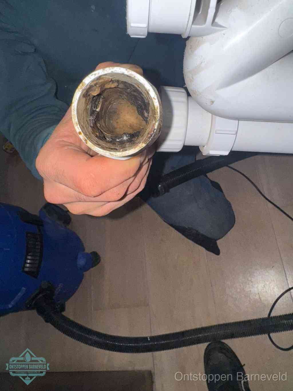Een losgekoppelde afvoerbuis die van binnen volledig is dichtgeslibd met vet en aanslag, de meest voorkomende oorzaak van een verstopte gootsteen in Barneveld