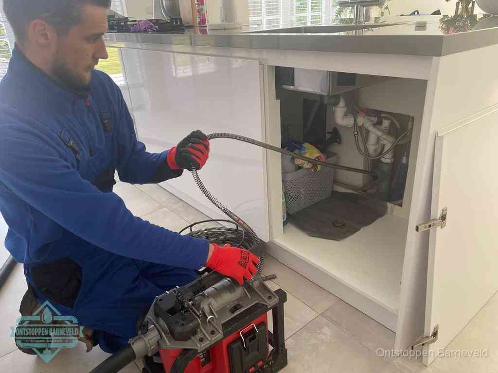 Een monteur reinigt de keukenafvoer grondig met een veermachine om terugkerende gootsteenverstoppingen te voorkomen in Barneveld