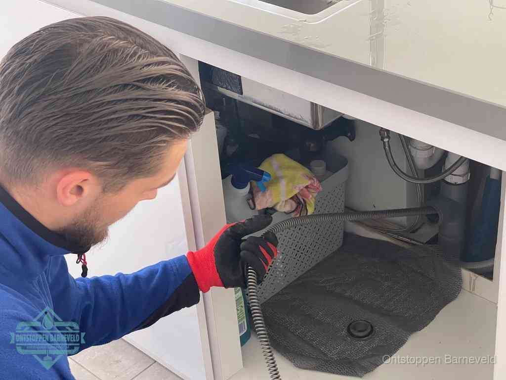 Een monteur voert een flexibele ontstoppingsveer in de afvoer om een verstopping voorbij de bocht van het toilet te bereiken in Barneveld