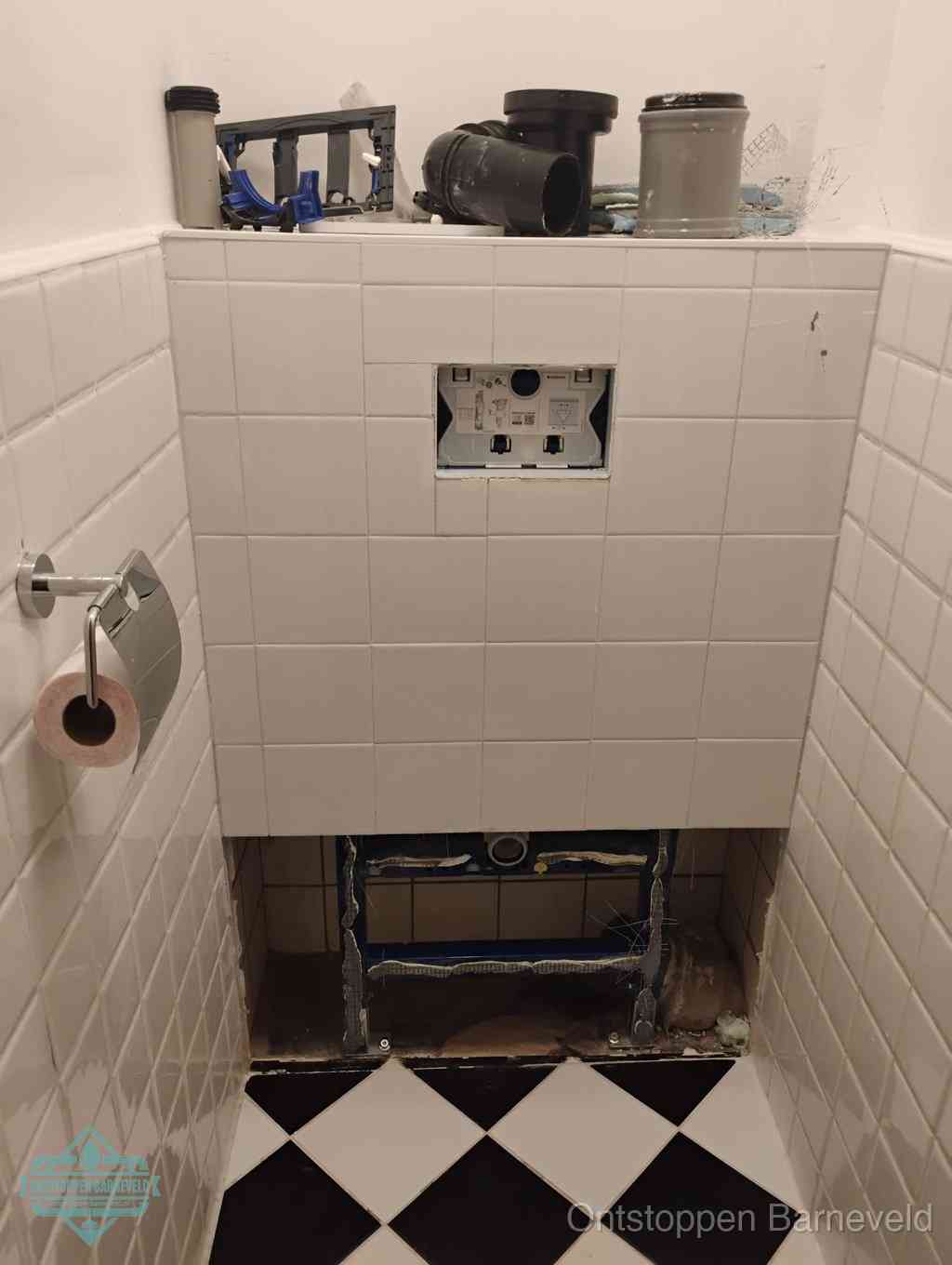Een toiletruimte waar het hangtoilet en de inbouwreservoir-onderdelen zijn vrijgelegd voor onderhoud, periodiek nazicht voorkomt een wc-verstopping in Barneveld